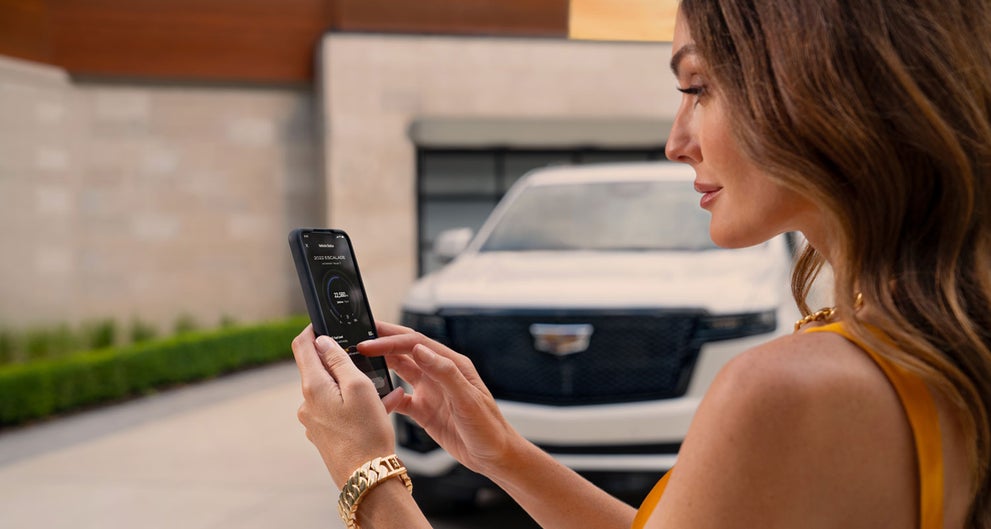 lady checking her mobile with a Cadillac vehicle background | Wallace Cadillac, LLC in Stuart FL