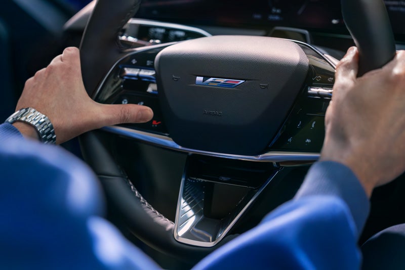 Close-up of a Man About to Press the V-Button on the 2026 OPTIQ-V Steering Wheel | Wallace Cadillac, LLC in Stuart FL